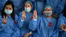 Tenaga medis mengenakan pita merah di seragamnya memberi hormat tiga jari di Rumah Sakit Umum Yangon di Yangon (3/2/2021). Mereka tidak akan menghentikan gerakan ini sampai pemerintahan terpilih dipulihkan. (STR / AFP)