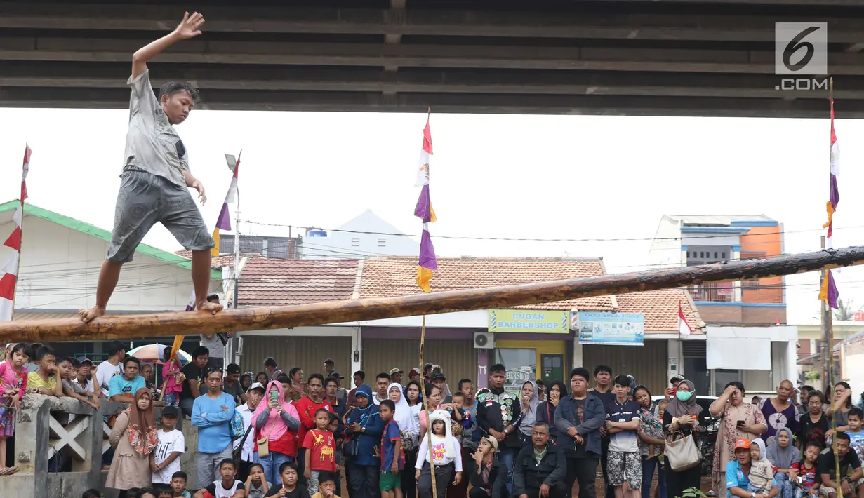 Anak-anak bermain lomba jalan di atas batang pohon pinang di sekitar Kalimalang, Jakarta, Sabtu (17/8/2019). Beragam lomba permainan digelar warga untuk menyemarakkan HUT ke-74 Republik Indonesia. (Liputan6.com/Helmi Fithriansyah)