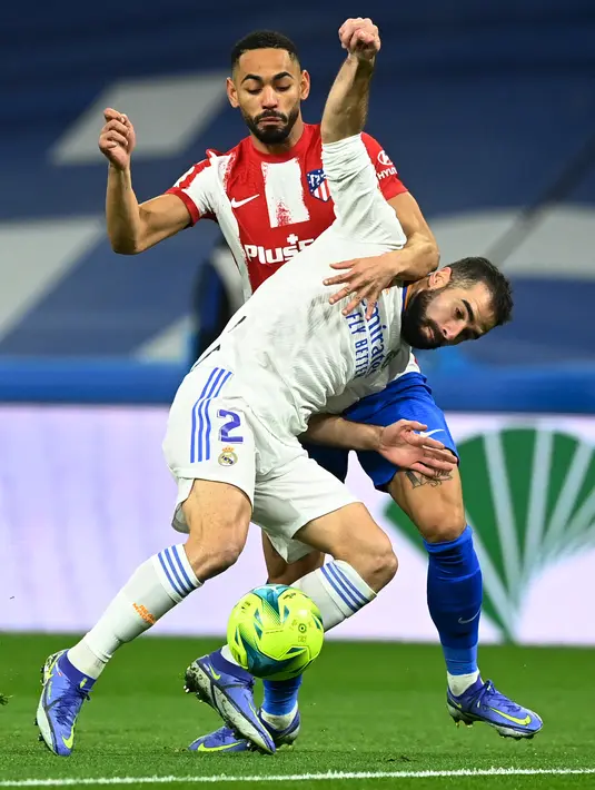 Bek Real Madrid Dani Carvajal (depan) bersaing dengan pemain depan Atletico Madrid Matheus Cunha pada pekan ke-17 Liga Spanyol di Santiago Bernabeu, Senin dini hari WIB (13/12/2021). Real Madrid berhasil menaklukkan rival sekotanya Atletico Madrid dengan skor 2-0. (OSCAR DEL POZO / AFP)
