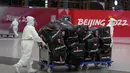 Pekerja Olimpiade dengan pakaian pelindung membantu para pelancong di bandara Internasional Ibu Kota Beijing setelah Olimpiade Musim Dingin 2022, di Beijing, China, Senin (21/2/2022). (APhoto/Frank Augstein)