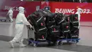 Pekerja Olimpiade dengan pakaian pelindung membantu para pelancong di bandara Internasional Ibu Kota Beijing setelah Olimpiade Musim Dingin 2022, di Beijing, China, Senin (21/2/2022). (APhoto/Frank Augstein)