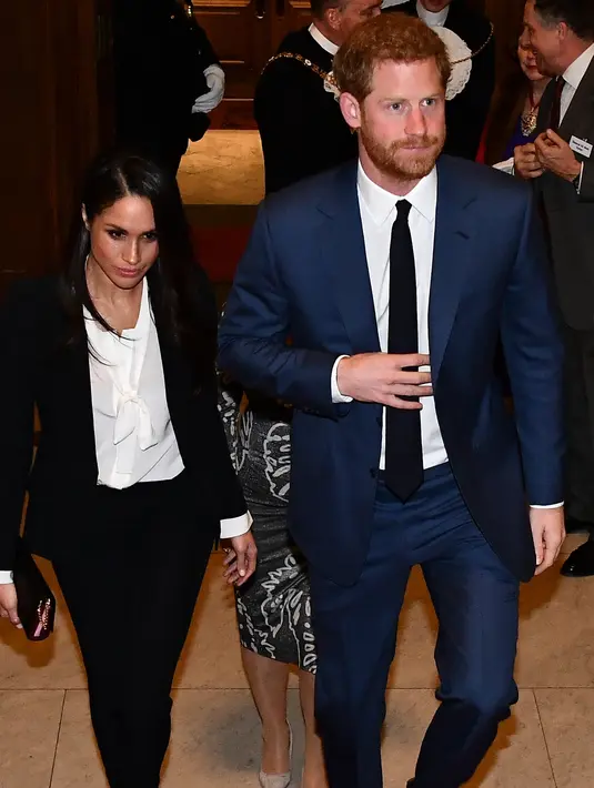 Pangeran Harry dan tunangannya, Meghan Markle menghadiri acara Endeavour Fund Awards di London, Kamis (1/2). Tak menggunakan gaun, Meghan Markle menjatuhkan pilihan pada mengenakan setelan celana panjang hitam dan shirt tuxedo. (Ben Stansall/pool via AP)