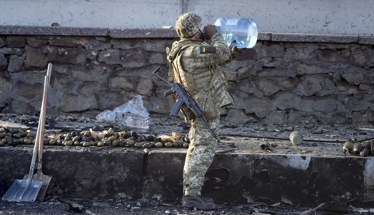 Tentara Ukraina minum air di dekat granat di sebuah jalan di Kyiv, Ukraina, Sabtu (26/2/2022). Pasukan Rusia menyerbu ke arah ibu kota Ukraina pada Sabtu (26/2), dan pertempuran jalanan pecah saat pejabat kota mendesak penduduk untuk berlindung. (AP Photo/Efrem Lukatsky)