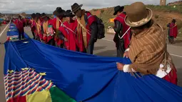 Seorang wanita menyatukan bagian-bagian bendera biru raksasa di jalan raya antara Oruro dan La Paz Bolivia (10/3). Gerakan ini untuk mendukung usaha negara Bolivia untuk mendapatkan akses berdaulat ke laut. (AP Photo / Juan Karita)