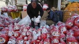 Seorang pedagang menata boneka merah Daruma yang dijajakan dalam pameran tahunan Oume Daruma di Tokyo, Jepang, 12 Januari 2018. Daruma atau boneka Dharma dijual dengan kedua belah mata yang belum digambar. (AP/Koji Sasahara)