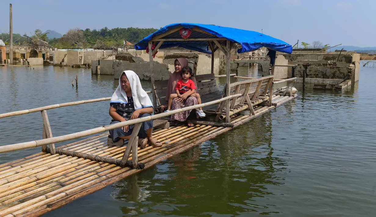 Warga menggunakan perahu  menyaksikan puing-puing  rumah yang kembali muncul di kawasan Bendungan Karian yang mengering di Kampung Somang, Lebak, Banten, Jumat, 7 Agustus 2026. (KLY/ Arie Basuki)