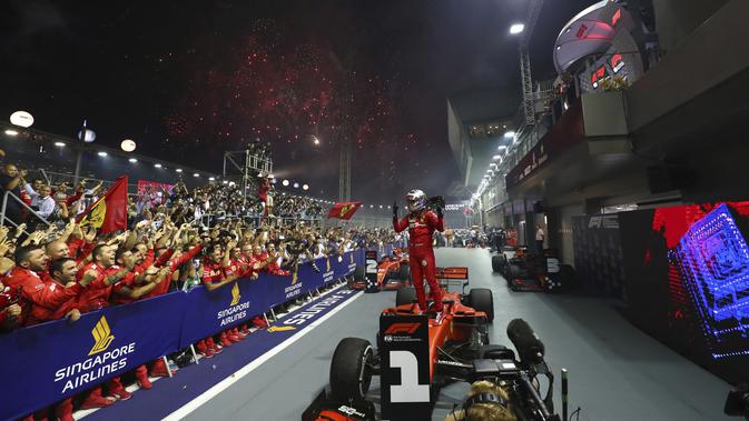 Pembalap Ferrari Sebastian Vettel berselebrasi di atas mobilnya setelah memenangkan balapan F1 GP Singapura di Sirkuit Jalan Marina Bay, Singapura (22/9/2019). Vettel kini memegang rekor kemenangan terbanyak di Singapura (2011, 2012, 2013, 2015,2019). (AP Photo/Lim Yong Teck)