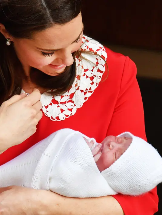 Duchess of Cambridge, Kate Middleton menggendong bayi ketiganya ketika akan meninggalkan Rumah Sakit St Mary's di Paddington, London, Senin (23/4). Kate yang memakai baju merah menggendong si kecil yang berselimut kain putih. (John Stillwell/Pool via AP)