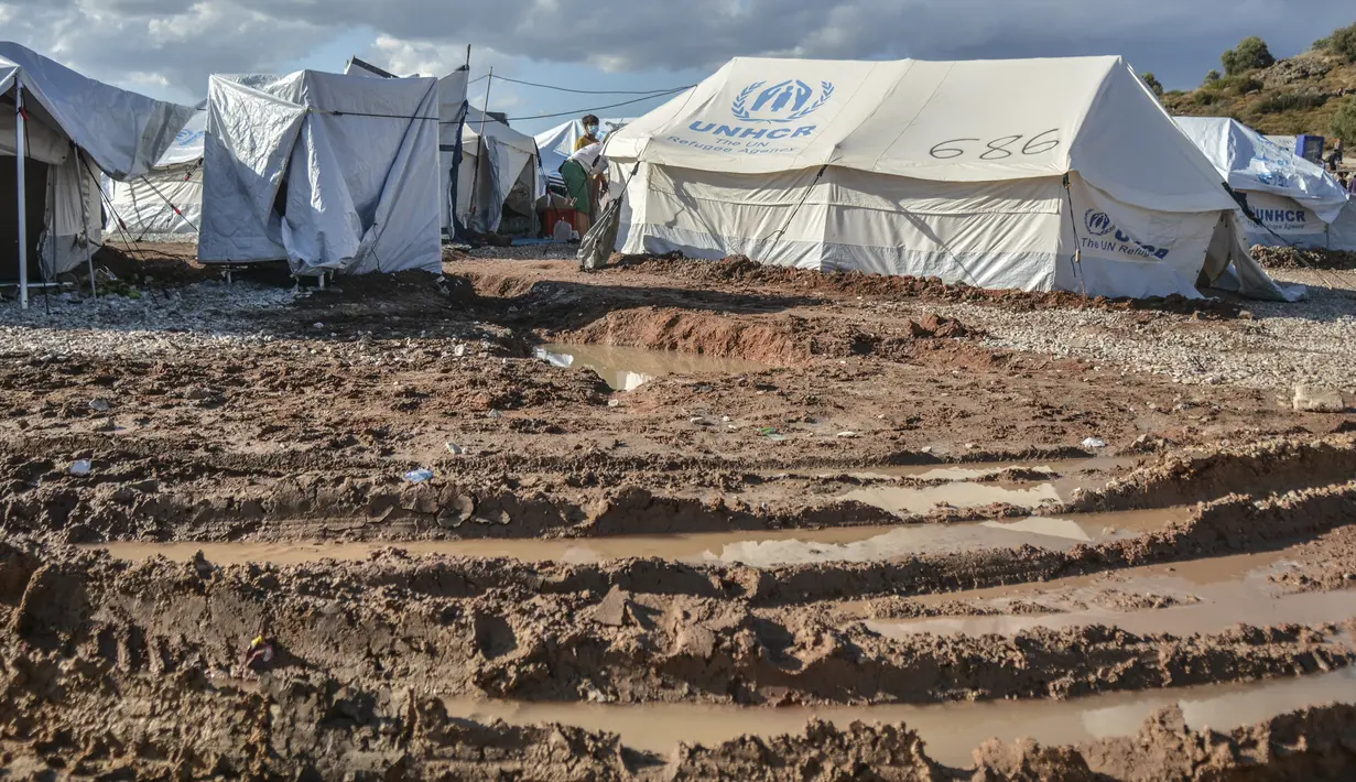 Para migran membersihkan tenda mereka, setelah hujan badai di kamp pengungsi Kara Tepe, di pulau Lesbos di timur laut Aegean, Yunani (14/10/2020).  (AP Photo/Panagiotis Balaskas)