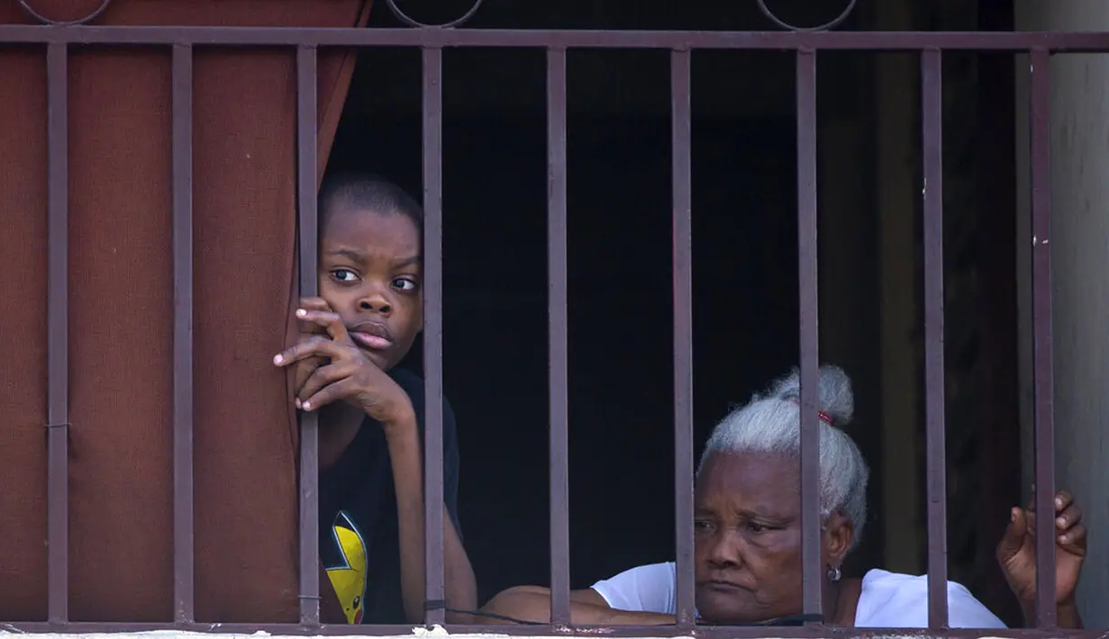 Warga menyaksikan pengunjuk rasa yang kesal dengan meningkatnya kekerasan membakar ban di lingkungan Lalue, Port-au-Prince, Haiti, Rabu (14/7/2021). Presiden Haiti Jovenel Moise dibunuh pada 7 Juli. Presiden Haiti Jovenel Moise dibunuh pada 7 Juli. (AP Photo/Joseph Odelyn)