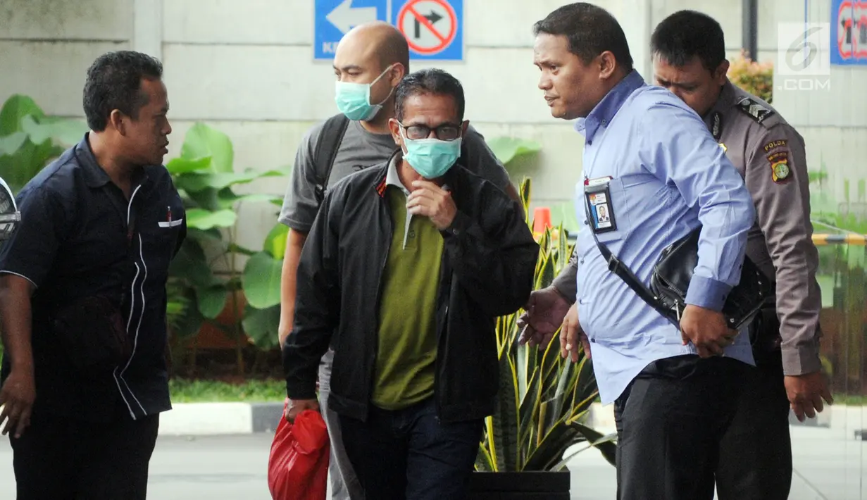 Bupati Mesuji Khamami (tengah) tiba di Gedung KPK, Jakarta, Kamis (24/1). Khamami menutupi wajahnya menggunakan masker. (Merdeka.com/Dwi Narwoko)
