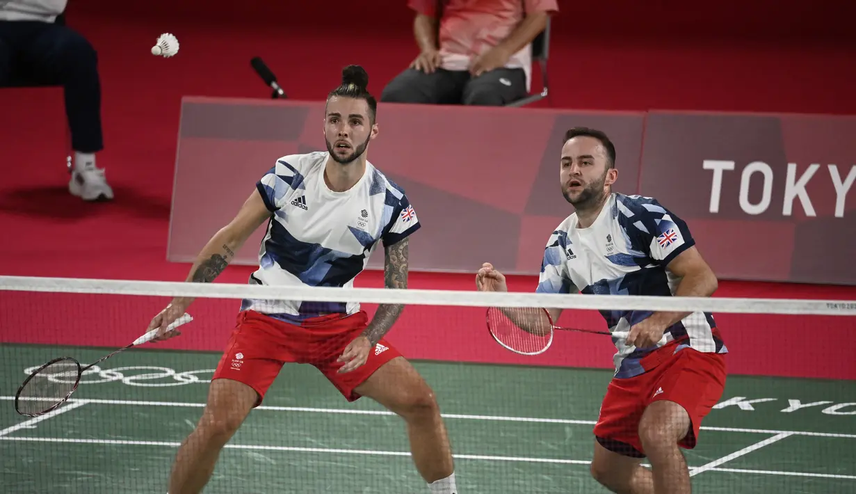 Ganda putra Inggris Ben Lane (kanan) dan Sean Vendy melawan Kevin Sanjaya Sukamuljo dan Marcus Gideon dari Indonesia pada pertandingan ganda putra Grup A Olimpiade Tokyo  2020 di Musashino Forest Sports Plaza, Sabtu (24/7/2021). Kevin / Marcus menang 21-15, 21-11. (Alexander NEMENOV/AFP)