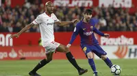 Pemain Barcelona, Lionel Messi (kanan) mengecoh pemain Sevilla, N'zonzi pada laga La Liga Santander di Sanchez Pizjuan stadium, (31/3/2018). Barcelona bermain imbang 2-2 dengan Sevilla. (AP/Miguel Morenatti)