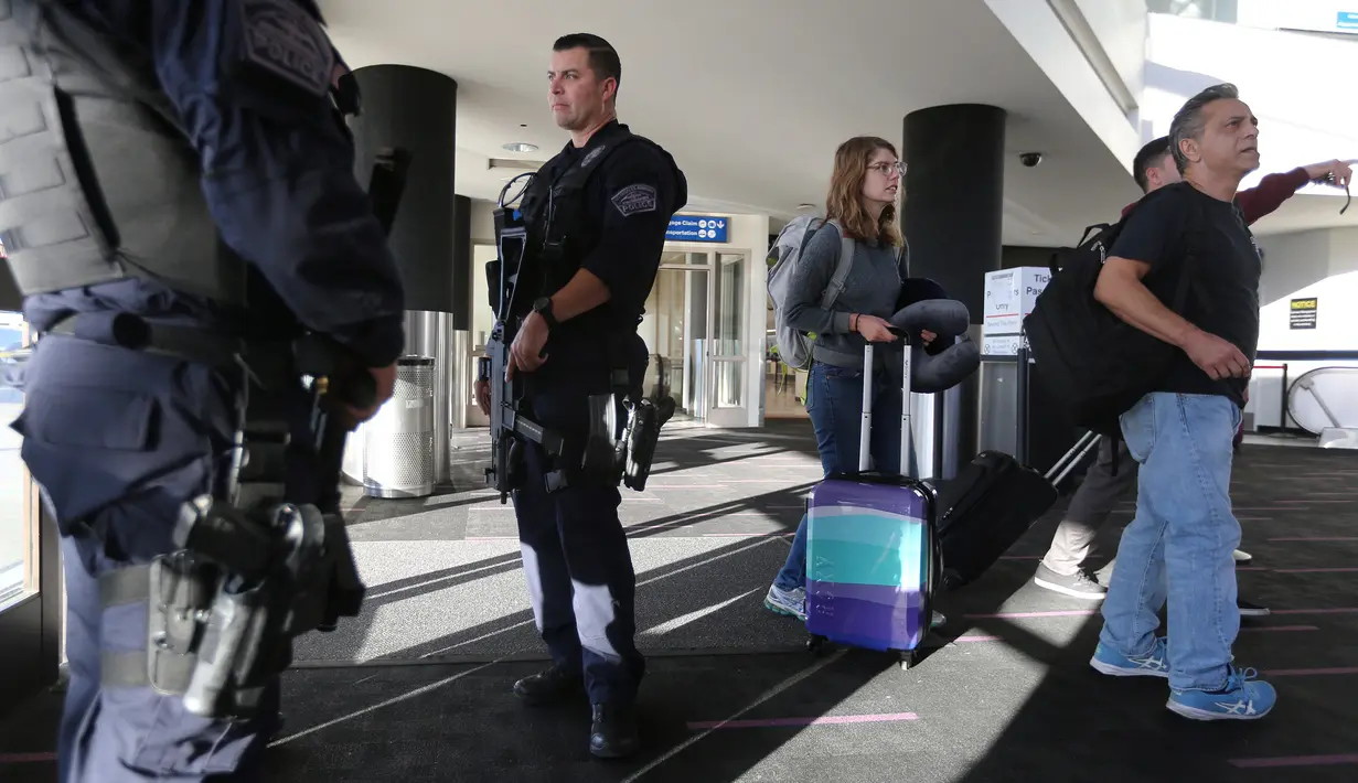Wisatawan melewati petugas keamanan Bandara Internasional Los Angeles (LAX) di Los Angeles, Rabu (23/11). Di Amerika Serikat, tradisi mudik dilakukan saat hari perayaan Thanksgiving yang jatuh setiap Kamis keempat di November. (REUTERS/David McNew)