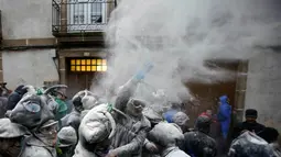 Peserta melemparkan tepung ke peserta lain dalam Festival O Entroido di Laza, Spanyol, Senin (8/2). Festival yang berlangsung selama seminggu itu dianggap sebagai peristiwa sosial dan budaya utama di kota Laza. (REUTERS/ Miguel Vidal)