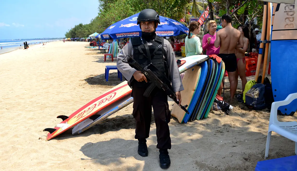 Petugas dengan senjata laras panjang dan rompi antipeluru berjaga di Pantai Kuta, Denpasar, Rabu (20/1). Polisi Indonesia mengumumkan bahwa mereka telah menangkap seorang pria yang membiayai serangan Jakarta mematikan. (AFP PHOTO/SONNY TUMBELAKA)