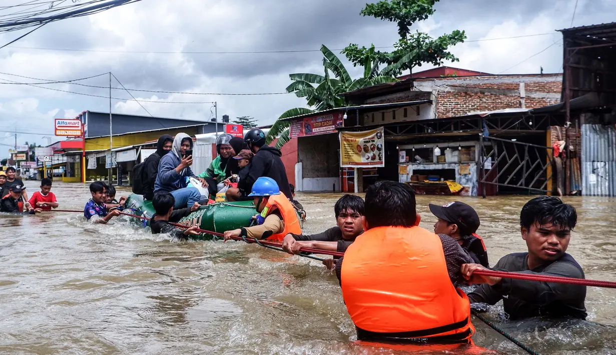 Para relawan membantu warga melewati derasnya banjir di Makassar pada 12 Februari 2025. (DAENG MANSUR/AFP)