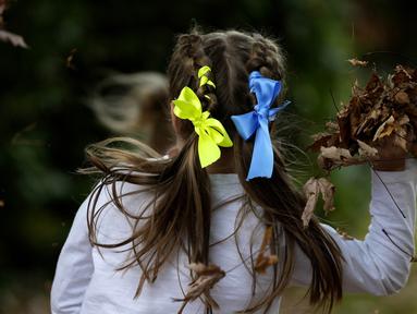 Anak-anak dengan pita warna nasional Ukraina di rambut mereka bermain di perayaan hari Kemerdekaan Ukraina di sebuah perayaan di Chichester, Inggris selatan, Sabtu, 27 Agustus 2022. Chichester dinobatkan sebagai daerah paling dermawan di negara itu untuk menampung pengungsi Ukraina. (AP Photo/Frank Augstein)
