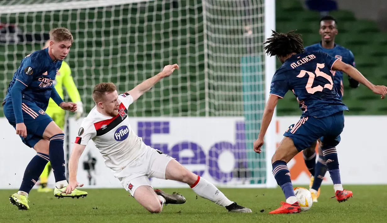 Bek Dundalk, Andy Boyle (kiri) bersaing dengan gelandang Arsenal, Mohamed Elneny pada pertandingan Grup B Liga Europa 2020/2021 di Stadion Aviva, Jumat (11/12/2020) dini hari WIB. Arsenal menang 4-2 saat bertandang di markas wakil Irlandia, Dundalk. (Paul Faith / AFP)