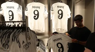 Seorang pria memegang jersey pemain sepak bola Prancis, Kylian Mbappe yang baru saja diluncurkan di toko resmi Real Madrid di stadion Santiago Bernabeu, Madrid, pada 11 Juli 2024. (Pierre-Philippe MARCOU/AFP)