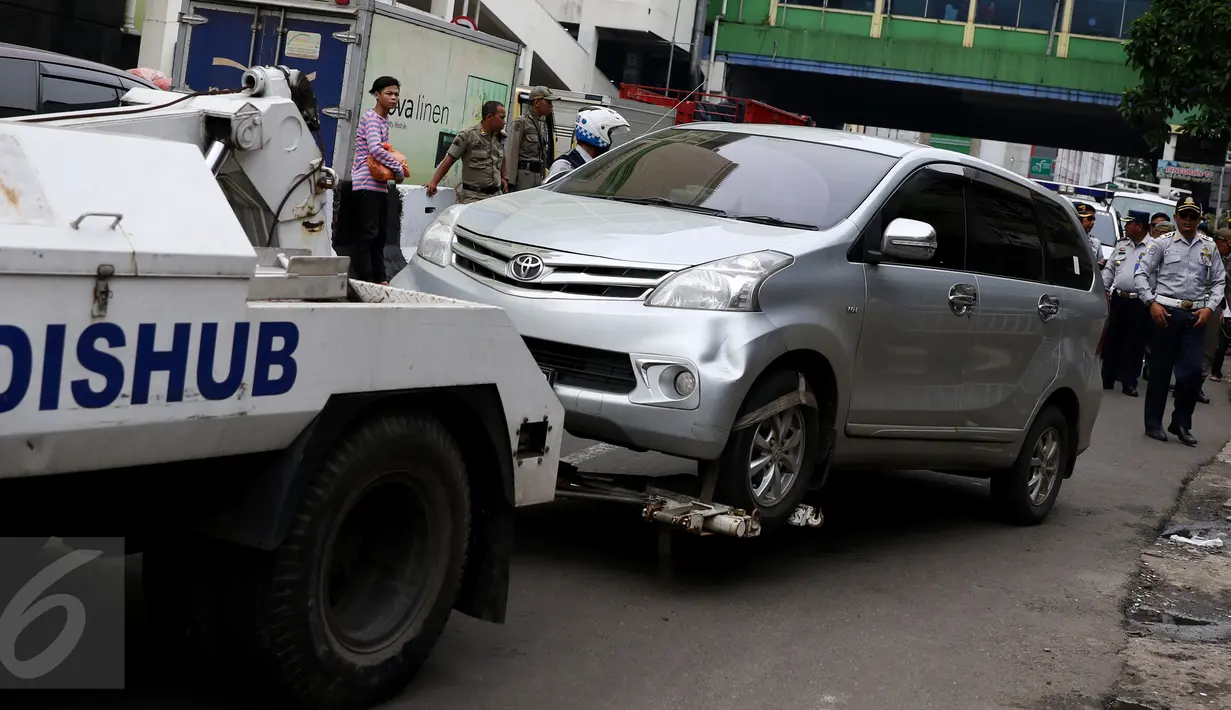 Petugas menderek kendaraan roda empat yang parkir sembarangan di kawasan Tanah Abang, Jakarta, Senin (14/11). Razia dilakukan menyusul maraknya parkir liar di kawasan Tanah Abang yang kerap menimbulkan kemacetan. (Liputan6.com/Gempur M Surya)