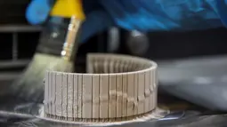 Seorang pekerja Comite Franceclat membersihkan bubuk emas ketika proses pembuatan gelang emas 'Dunes' dengan mesin cetak 3D di laboratorium penelitian 'Franceclat', Besancon, Prancis timur, 11 Oktober 2017. (AFP FOTO / SEBASTIEN BOZON)