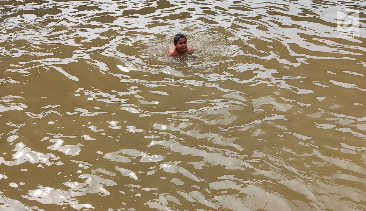 Anak-anak berenang di Sungai Kalimalang, Jakarta Timur, Jumat (5/7/2019). Tingginya suhu udara Ibu Kota akibat musim kemarau menyebabkan anak-anak tersebut berenang di Sungai Kalimalang meski dengan kondisi seadanya. (Liputan6.com/Immanuel Antonius)