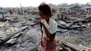 Seorang wanita berjalan di antara puing-puing setelah kebakaran sebuah kamp bagi pengungsi Muslim Rohingya di negara bagian Rakhine, Myanmar, Selasa (3/5). Kebakaran menghancurkan 50 hunian sementara dalam kamp bagi pengungsi asing. (REUTERS/Soe Zeya Tun)