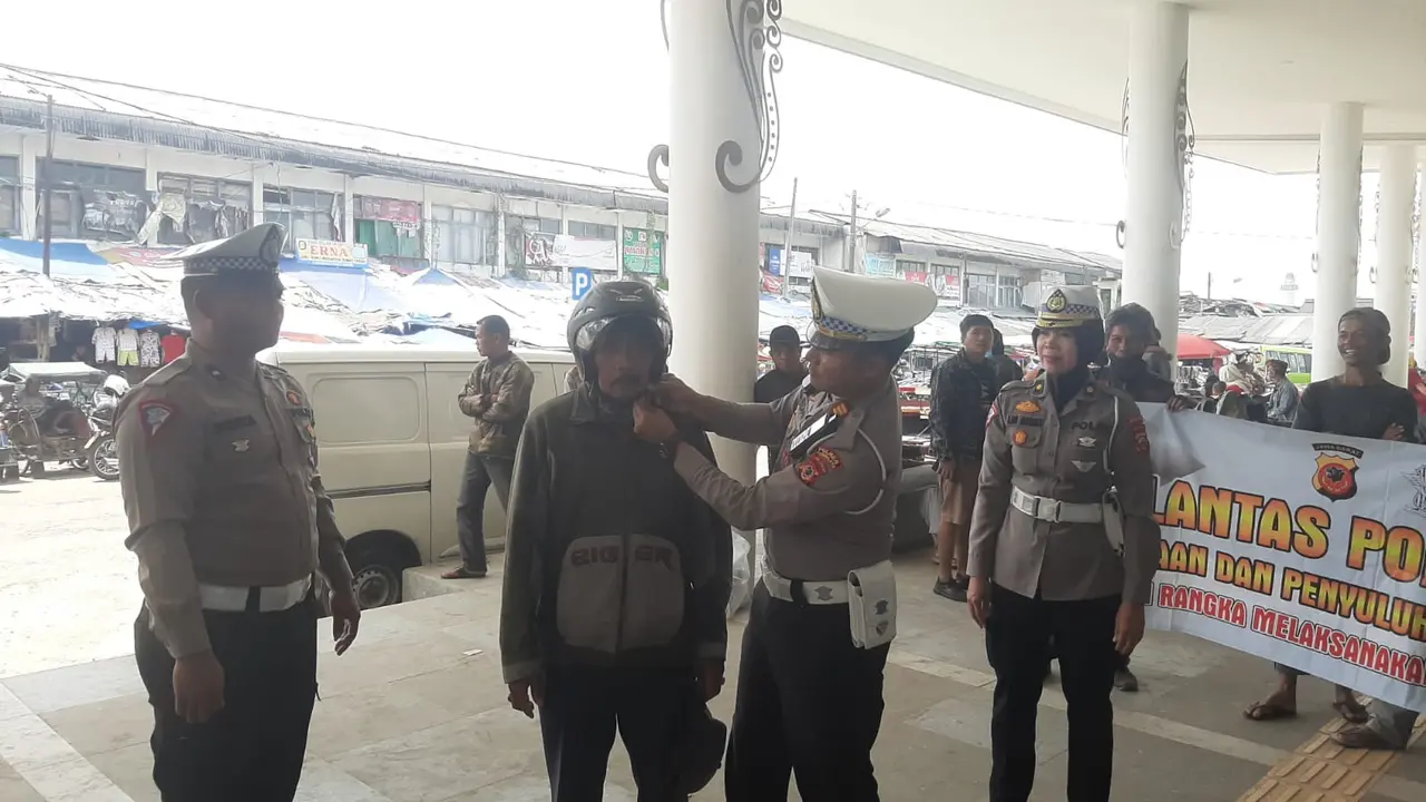 Dua orang petugas Satlantas Polres Tasik tengah memasangkan helm SNI secara gratis kepada salah seorang driver ojek online (ojol) Tasikmalaya, Jawa Barat. (Liputan6.com/Jayadi Supriadin)