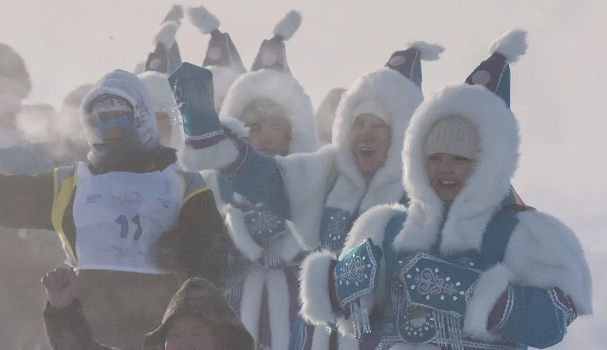 Wanita berkostum nasional Yakutian mendukung pelari yang sedang ambil bagian dalam maraton terdingin di dunia internasional pada suhu minus 53 derajat (-63,4 Fahrenheit) di dekat Oymyakon, republik Sakha, juga dikenal sebagai Yakutia, Timur Jauh Rusia, Sabtu, 22 Januari 2022. (AP/Ivan Nikiforov)