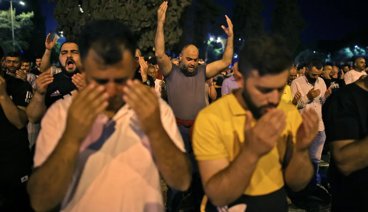 Umat muslim Palestina terlihat khusyuk berdoa saat berburu Lailatul Qadar di malam ganjil 27 Ramadan di luar Kubah Batu (Dome of the Rock) di kompleks Masjid Al-Aqsa di Yerusalem (8/5/2021). (AFP/Ahmad Gharabli)