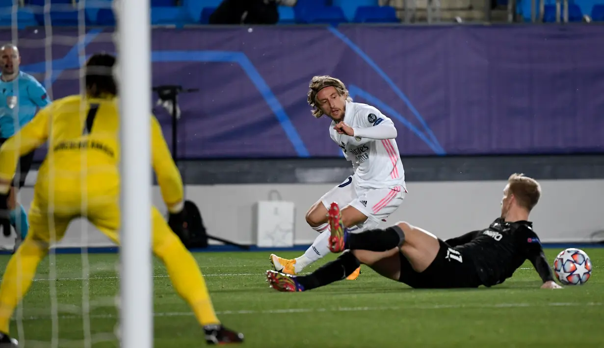 Gelandang Real Madrid, Luka Modric berusaha melewati pemain Borussia Monchengladbach, Oscar Wendt pada pertandingan Grup B Liga Champions di Estadio Alfredo Di Stefano, Kamis (10/12/2020). Kemenangan ini mengantar Madrid lolos ke babak 16 besar Liga Champions. (AFP/PIERRE-PHILIPPE MARCOU)