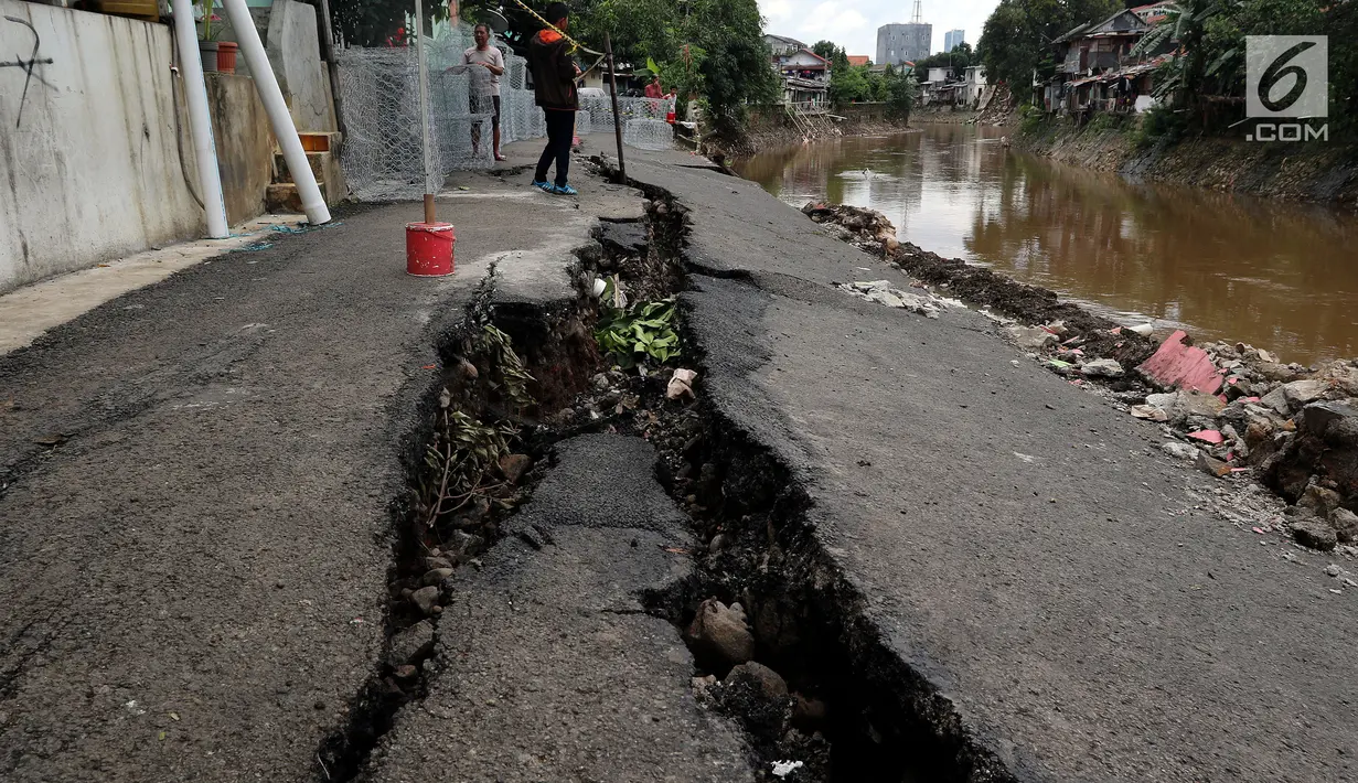 Kondisi jalan retak di Kelurahan Kebon Manggis, Kecamatan Matraman, Jakarta Timur, Jumat (16/2). Sejauh ini, dinas yang dibantu warga masih mengerjakan sisi dari sungai guna mencegah keretakan jalan lebih lebar. (Liputan6.com/Johan Tallo)