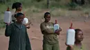 Para penjaga membawa botol bersisi susu formula untuk memberi makan anak-anak gajah di Reteti Elephant Sanctuary, Namunyak Wildlife Conservancy, Kenya, Rabu (26/2/2020). Anak-anak gajah akan dilepaskan kembali ke alam liar ketika mendekati usia empat tahun. (TONY KARUMBA/AFP)