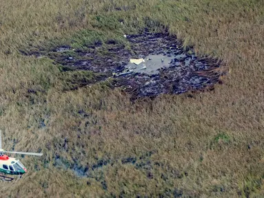 Helikopter terbang di atas puing-puing pesawat Beechcraft Baron yang jatuh dekat bandara di Ayolas, Paraguay, Kamis (26/7). Kecelakaan tersebut menewaskan empat orang. (Carlos Juri/Grupo La Nacion/AFP)