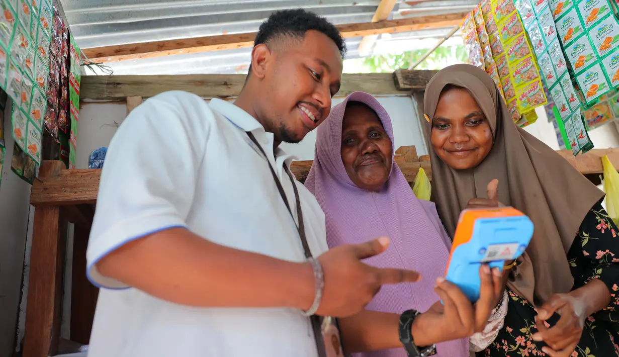 Ragaia Sosir melayani konsumen menggunakan mesin EDC BRI di kiosnya di Kampung Arar. Melalui layanan BRILink Agen, warga dapat melakukan berbagai transaksi tanpa harus bepergian jauh ke luar kampung. (Sumber: BRI/Advertorial)