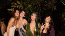 Bersama tiga tamu lain, Kim berpose ceria dengan gaun hijau metaliknya. Di sebelahnya, tampil gaun slip panjang krem berbahan rajut bertekstur, gaun satin biru dengan panel renda warna nude dan heels transparan, serta mini dress ungu plum berhias bulu di bagian dada dengan clutch satin hitam. [@kimkardashian]