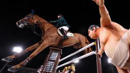 Marlon Modolo Zanotelli dari Brasil mengendarai Edgar M melewati patung pegulat sumo dalam kualifikasi individu lompat berkuda Olimpiade Tokyo 2020 di Equestrian Park di Tokyo (3/8/2021). Pihak panitia memasang patung simbol Jepang seperti sakura sampai pesumo di arena lintasan. (AFP/Behrouz Mehri)