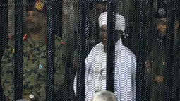 Presiden terguling Sudan, Omar al-Bashir ditempatkan di kandang terdakwa selama menjalani persidangan atas dakwaan korupsi di pengadilan di Khartoum, Senin (19/8/2019). Bashir  didakwa dengan tuduhan korupsi, kepemilikan mata uang asing dan menerima gratifikasi. (Ebrahim HAMID / AFP)