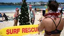Seorang wanita mengenakan topi santa berjemur selama  Hari Natal 2018 di Pantai Bondi di Sydney, Australia (25/12). (AFP Photo/Peter Parks)