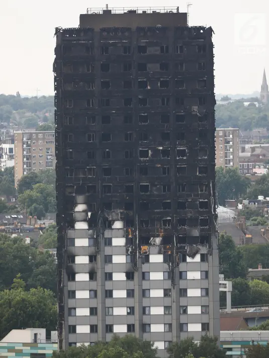Kerusakan bangunan apartemen Grenfell Tower di London terlihat dari utara Kensington, Minggu (18/6). Gedung apartemen Grenfell Tower yang terbakar pada lepas tengah malam Rabu 14 Juni 2017 lalu dikhawatirkan roboh usai habis dilahap api. (TOLGA AKMEN/AFP)
