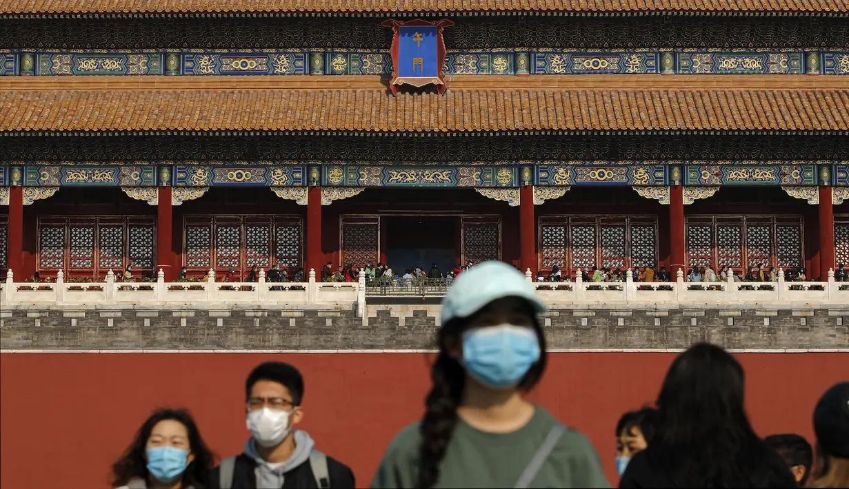 Turis mengenakan masker untuk mencegahn penyebaran virus corona hingga memasuki Kota Terlarang di Beijing (25/10/2020). Dengan wabah COVID-19 yang sebagian besar terkendali di dalam perbatasan China, rutinitas kehidupan sehari-hari yang normal telah mulai kembali untuk warganya. (AP Photo/Andy Wong)