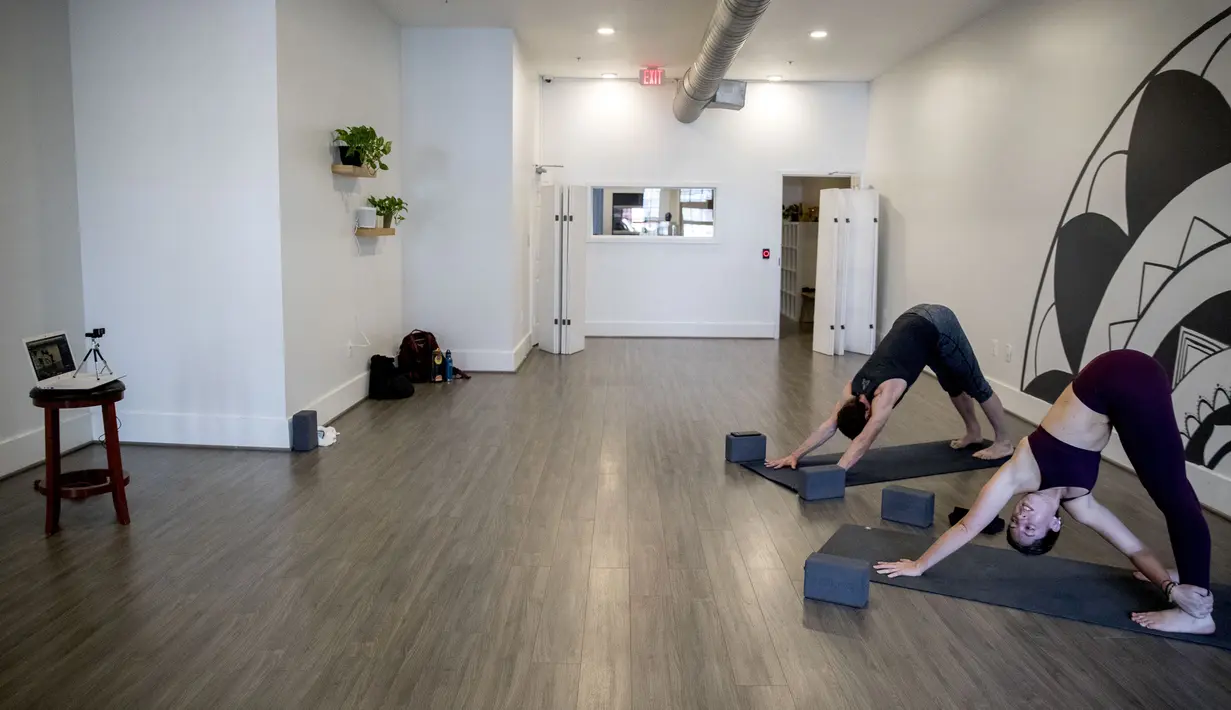 Pemilik Elyse DiBartolo (kanan) dan instruktur Brendan Smullen mengadakan kelas yoga online melalui webcam di Haus Yoga, H Street, Washington, Amerika Serikat, Selasa (17/3/2020). Kelas yoga online ini dilakukan setiap hari selama karantina virus corona COVID-19. (AP Photo/Andrew Harnik)