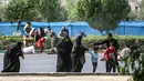 Seorang pria membantu wanita dan anak-anak melarikan diri saat terjadi serangan pada parade militer di Ahvaz, Iran, Sabtu (22/9). Hampir separuh yang tewas dalam serangan Ahvaz adalah anggota Garda Revolusi. (MORTEZA JABERIAN/ISNA/AFP)