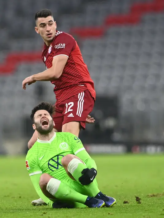Gelandang Bayern Munchen Marc Roca (kiri) berebut bola dengan gelandang VfL Wolfsburg Renato Steffen pada pekan ke-17 Liga Jerman di Allianz Arena Sabtu (18/12/2021) dinihari WIB. Bayern mencukur Wolfsburg dengan skor 4-0. (Christof STACHE / AFP)