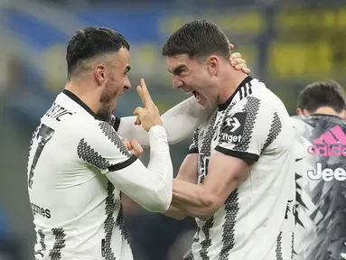 Gelandang Juventus, Filip Kostic berselebrasi dengan Dusan Vlahovic setelah mencetak gol pembuka timnya ke gawang Inter Milan pada laga Liga Italia atau  Serie A 2022/2023 giornata ke-27 di Stadio Giuseppe Meazza, Senin (20/3/2023) dini hari WIB. (AP Photo/Antonio Calanni)