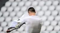 Striker Juventus, Cristiano Ronaldo melepas jersey untuk diberikan kepada seorang ball boy usai berakhirnya laga melawan Genoa dalam lanjutan Liga Italia 2020/2021 pekan ke-30 di Allianz Stadium, Turin, Minggu (11/4/2021). Juventus menang 3-1 atas Genoa. (AFP/Marco Bertorello)