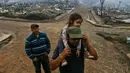 Sergio Gelvez membawa putrinya Maite Gelvez usai kebakaran yang melanda tempat tinggalnya di Santa Olga, Chile, (26/1). Sebanyak 6.000 warga berhasil menyelamatkan diri dari kebakaran hebat tersebut. (AP Photo/Esteban Felix)