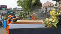 Petugas menyemprotkan cairan disinfektan ke peti mati di Kawasan Kalisari, Pasar Rebo, Jakarta Timur, Kamis (3/9/2020). Warga Kelurahan Pasar Rebo yang tidak menggunakan masker diberikan pilihan hukuman, salah satunya dimasukkan ke dalam peti mati selama 1 menit. (Liputan6.com.Herman Zakharia)