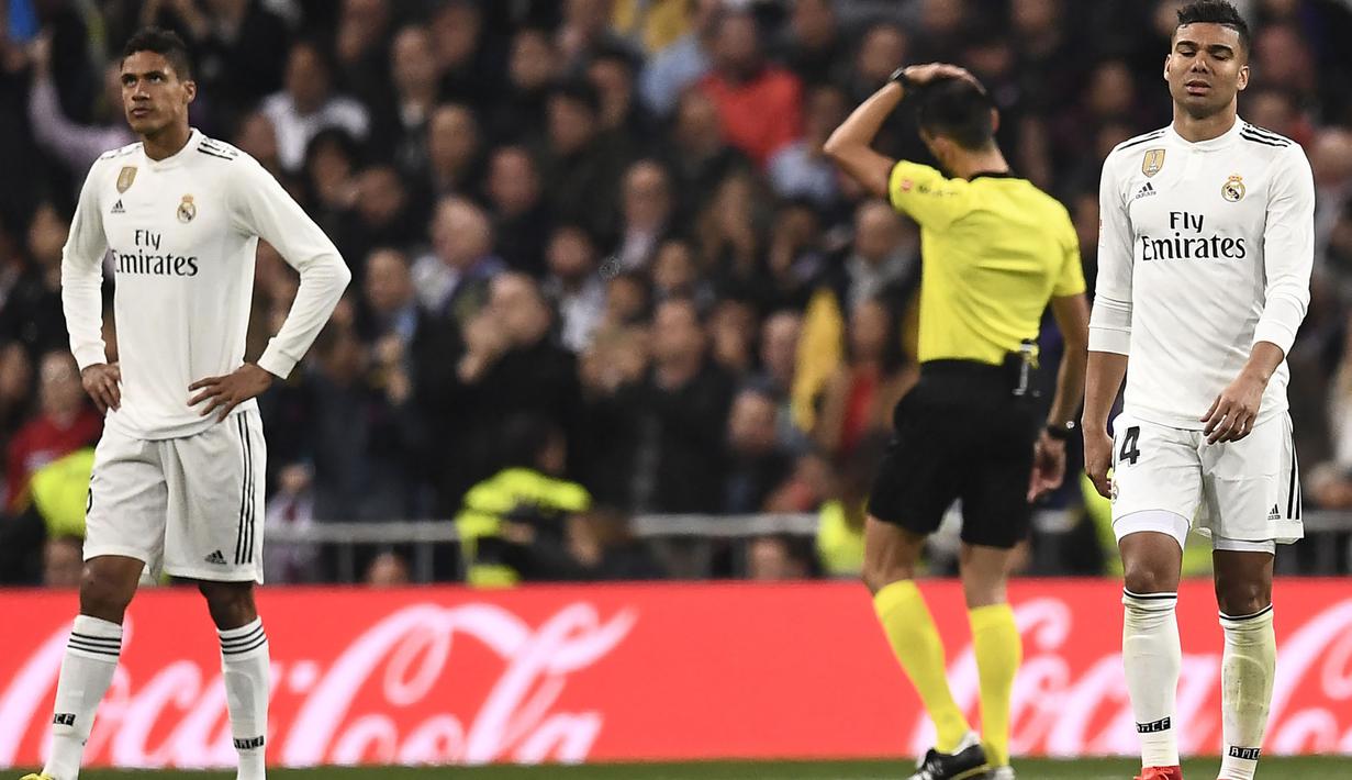 Bek Real Madrid, Raphael Varane (kiri) mencetak gol bunuh diri saat laga El Clasico menghadapi Barcelona pada laga leg kedua semifinal Copa del Rey 2018/2019 (28/2/2019). Gol bunuh diri tersebut terjadi pada menit ke-69 saat Real Madrid telah tertinggal 0-1. Hasil akhir, Real Madrid kalah 0-3 dari Barcelona. (AFP/Oscar Del pozo)
